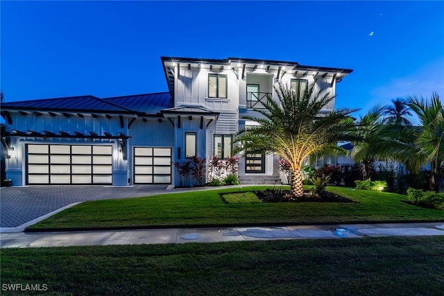 view of front of home with a garage, a balcony, and a front lawn