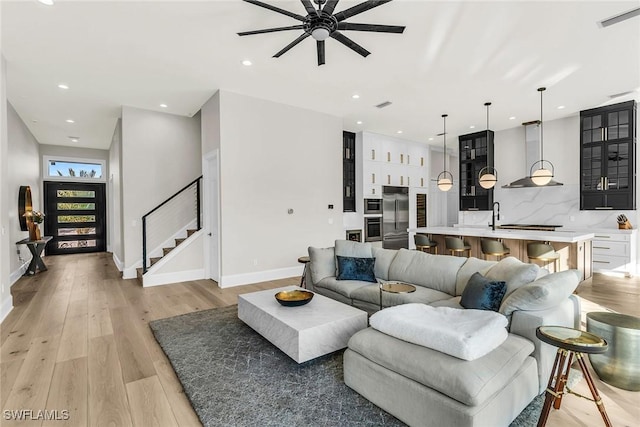 living room with ceiling fan, light wood-type flooring, and sink