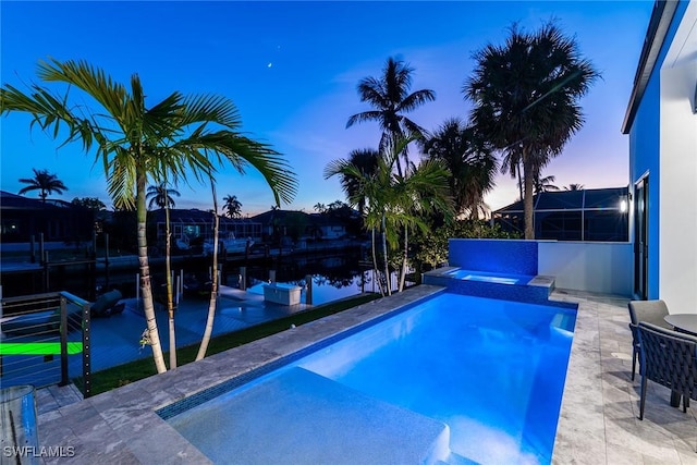 pool at dusk with an in ground hot tub and a water view