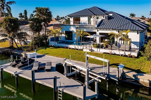 view of dock with a water view, a yard, a balcony, and a patio