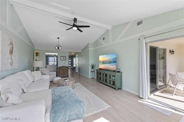 living room with lofted ceiling with beams, ceiling fan with notable chandelier, and light wood-type flooring