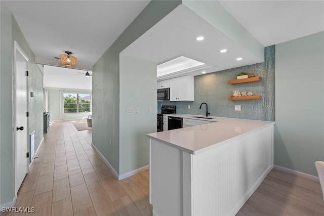 kitchen featuring kitchen peninsula, white cabinetry, sink, ceiling fan, and black appliances