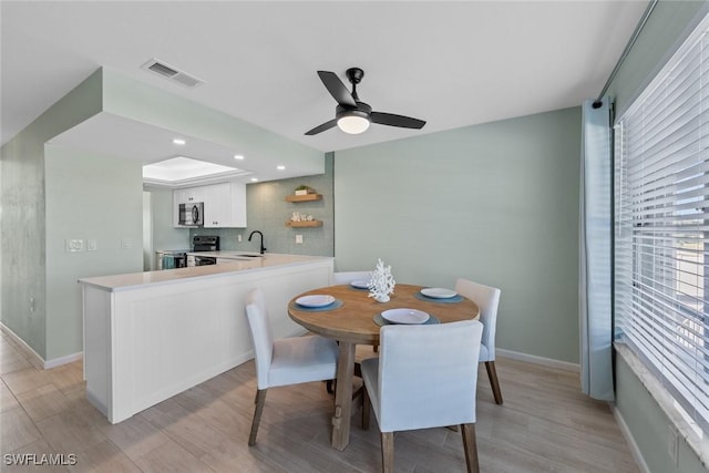 dining area with sink, light hardwood / wood-style floors, and ceiling fan