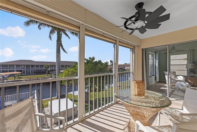 sunroom featuring a water view and ceiling fan