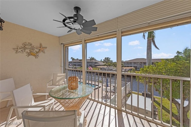 sunroom featuring ceiling fan and a water view