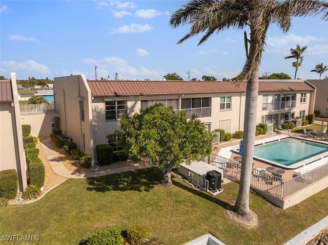 rear view of property featuring a community pool and a yard