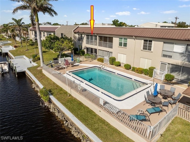 view of pool with a water view, a yard, a dock, and a patio area