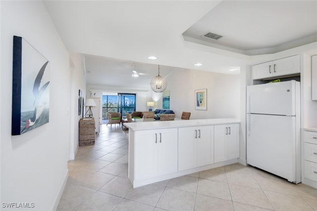 kitchen with an inviting chandelier, white cabinets, white refrigerator, light tile patterned floors, and kitchen peninsula