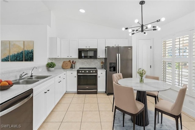 kitchen with stainless steel appliances, pendant lighting, white cabinets, and light tile patterned floors