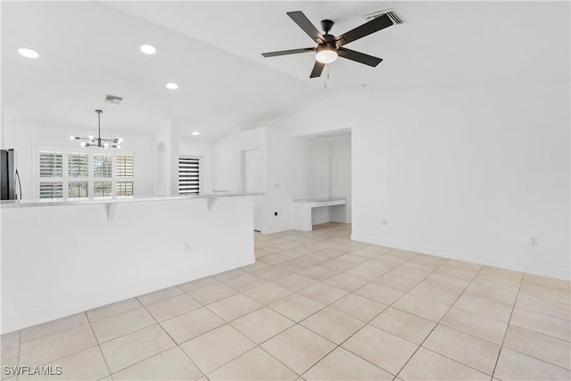 spare room featuring vaulted ceiling, ceiling fan with notable chandelier, and light tile patterned flooring