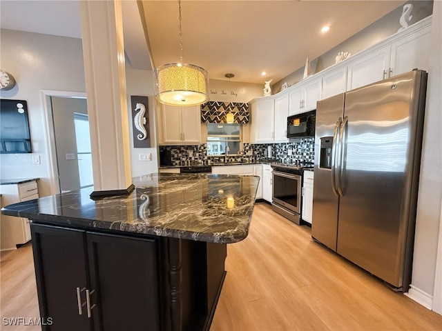 kitchen featuring appliances with stainless steel finishes, white cabinetry, sink, dark stone countertops, and hanging light fixtures