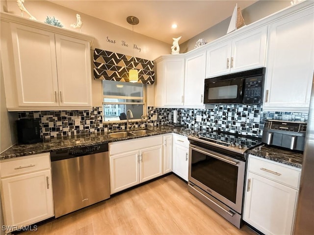 kitchen featuring dark stone countertops, stainless steel appliances, decorative light fixtures, and white cabinets