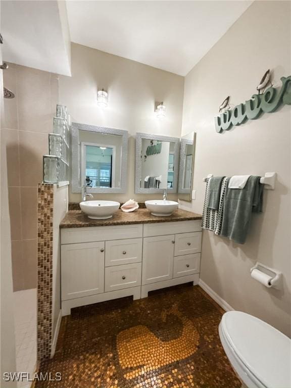 bathroom featuring vanity, tiled shower, and toilet