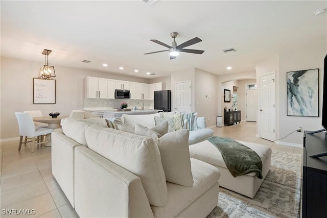 tiled living room featuring ceiling fan and sink