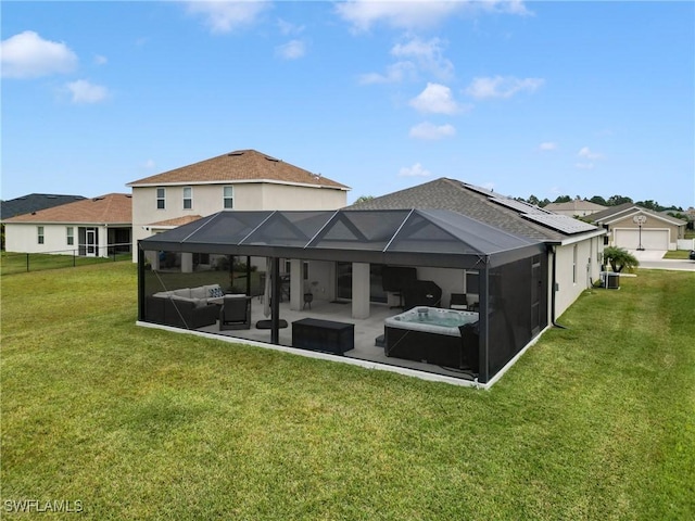 rear view of property featuring glass enclosure, a yard, a hot tub, and solar panels