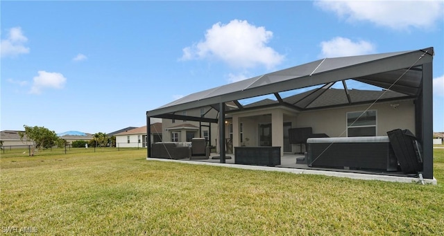 back of property with glass enclosure, a yard, and a hot tub