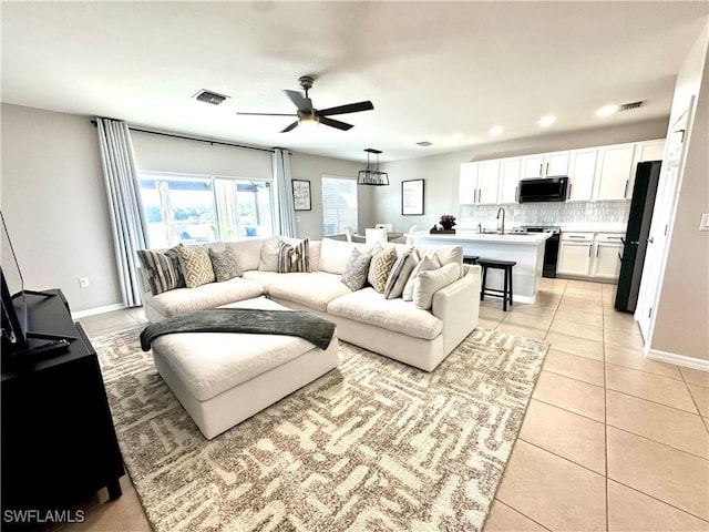 living room featuring ceiling fan, sink, and light tile patterned floors