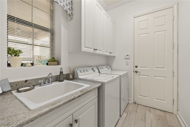 laundry area featuring separate washer and dryer, cabinets, sink, light wood-type flooring, and crown molding