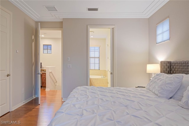 bedroom with connected bathroom, crown molding, hardwood / wood-style floors, and multiple windows