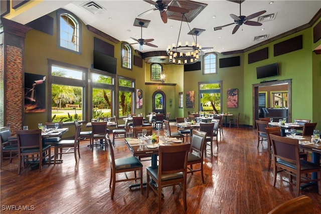 dining area featuring wood-type flooring, a towering ceiling, and a healthy amount of sunlight