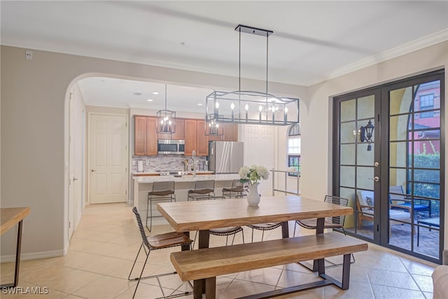 dining room featuring crown molding, french doors, light tile patterned flooring, and a notable chandelier