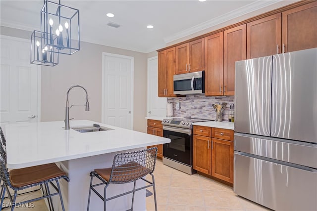 kitchen with sink, stainless steel appliances, decorative light fixtures, a breakfast bar area, and a center island with sink