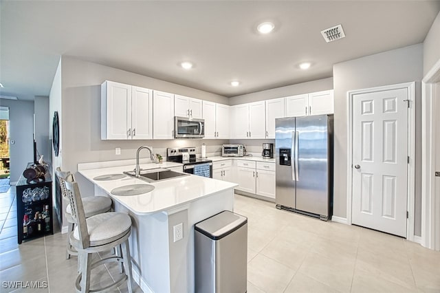 kitchen with a breakfast bar, appliances with stainless steel finishes, white cabinets, and sink