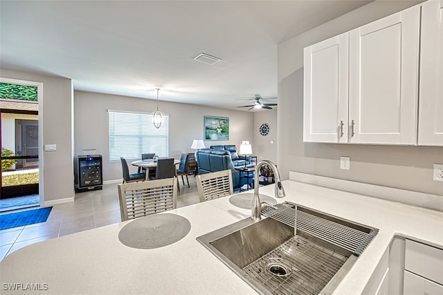 kitchen with ceiling fan, sink, light tile patterned floors, white cabinets, and hanging light fixtures