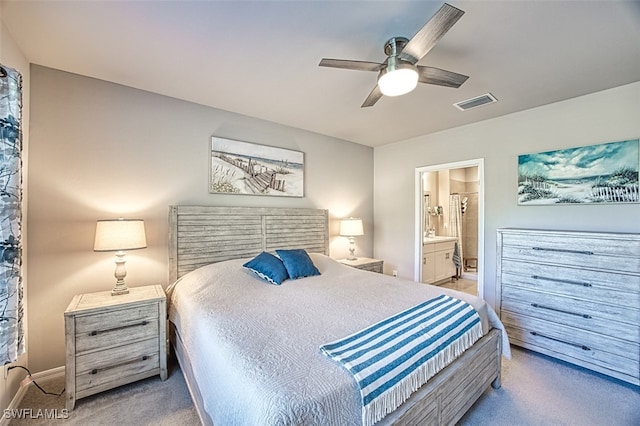 bedroom with ceiling fan, light colored carpet, and connected bathroom