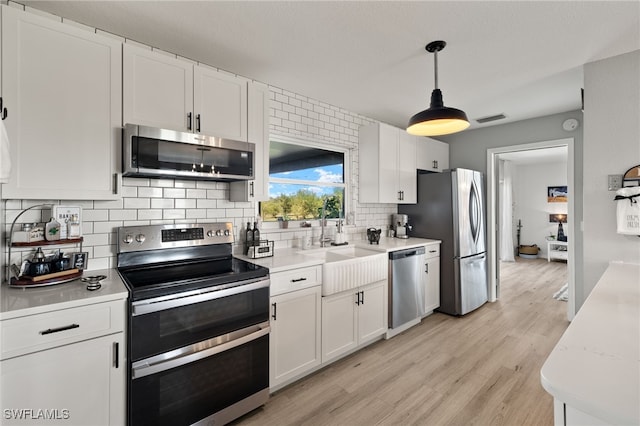 kitchen with white cabinets, decorative backsplash, pendant lighting, and stainless steel appliances