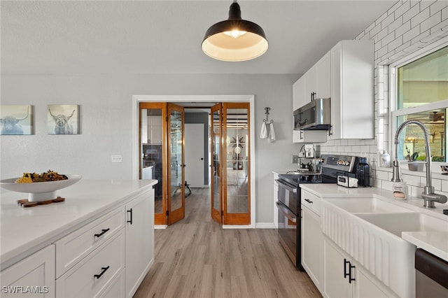 kitchen featuring sink, tasteful backsplash, pendant lighting, white cabinets, and appliances with stainless steel finishes