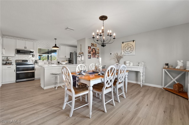 dining room with light hardwood / wood-style floors and an inviting chandelier