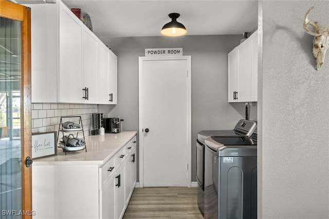 washroom with light hardwood / wood-style floors, cabinets, and separate washer and dryer