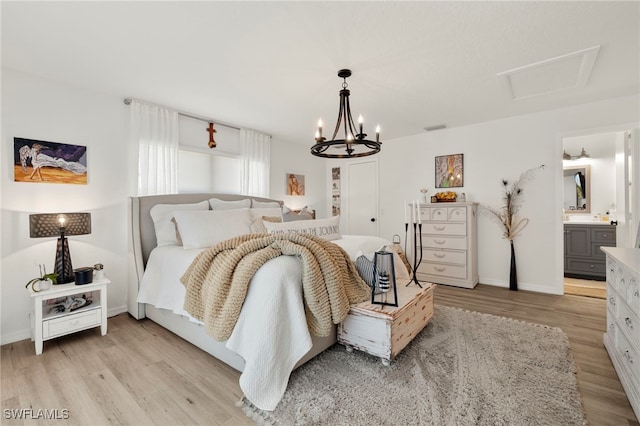 bedroom featuring an inviting chandelier, light hardwood / wood-style flooring, and ensuite bath