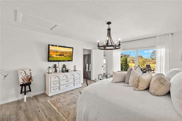 bedroom with a chandelier, a textured ceiling, stainless steel refrigerator, and light hardwood / wood-style flooring