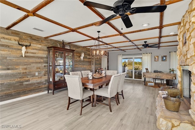 dining room featuring wooden walls, light hardwood / wood-style flooring, ceiling fan with notable chandelier, and coffered ceiling