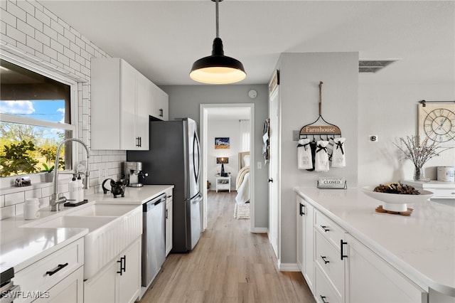 kitchen featuring decorative backsplash, pendant lighting, white cabinets, and dishwasher