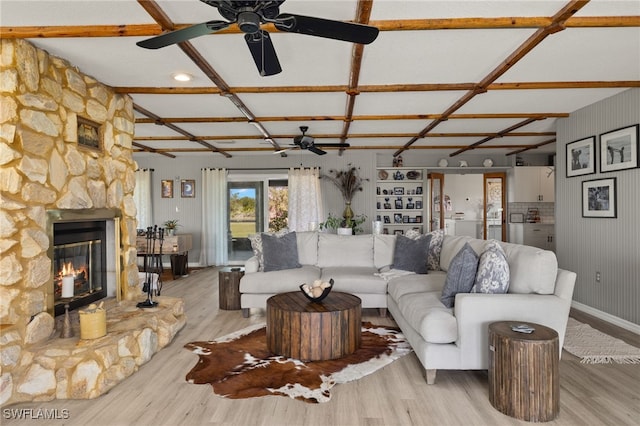 living room with light hardwood / wood-style floors, a stone fireplace, and coffered ceiling