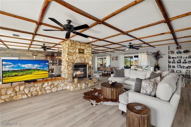 living room featuring a stone fireplace, coffered ceiling, and hardwood / wood-style flooring