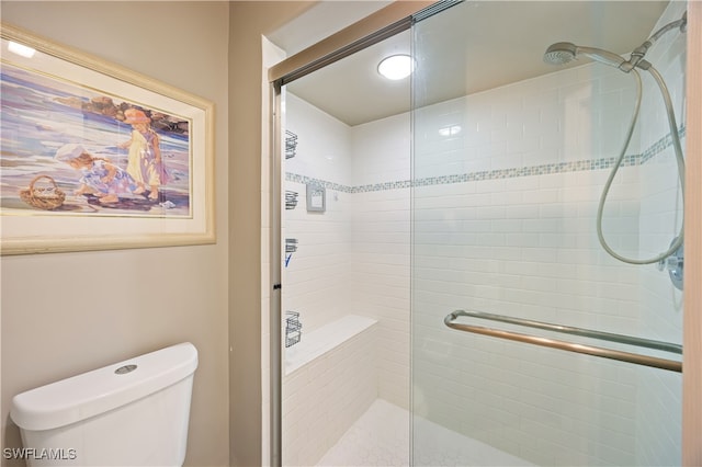 bathroom featuring toilet and a shower with door