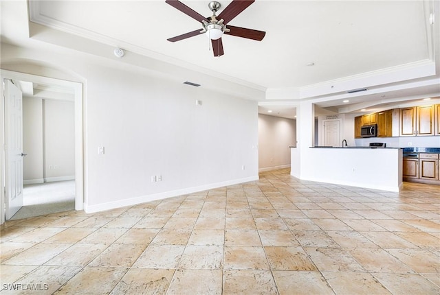 unfurnished living room featuring a raised ceiling, crown molding, and ceiling fan