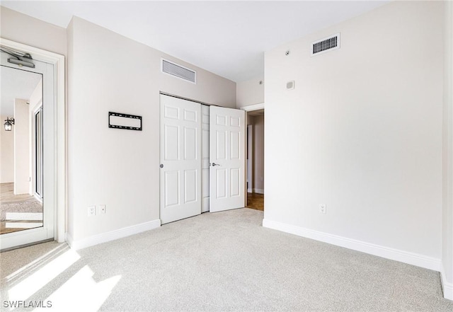 unfurnished bedroom with light carpet and a closet