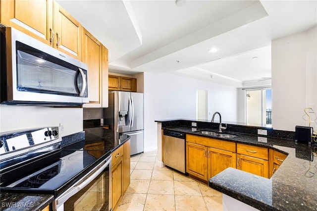 kitchen featuring a raised ceiling, sink, dark stone counters, and appliances with stainless steel finishes