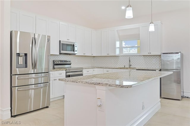 kitchen with a kitchen island, appliances with stainless steel finishes, pendant lighting, sink, and white cabinets