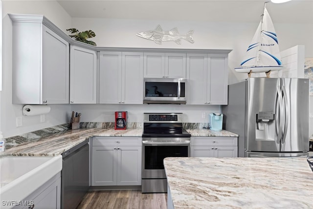 kitchen featuring gray cabinetry, light stone counters, stainless steel appliances, and dark hardwood / wood-style floors