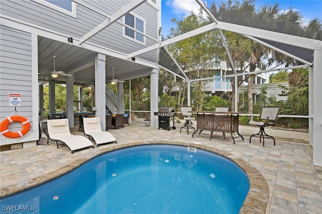 view of pool with a patio area, ceiling fan, area for grilling, and glass enclosure