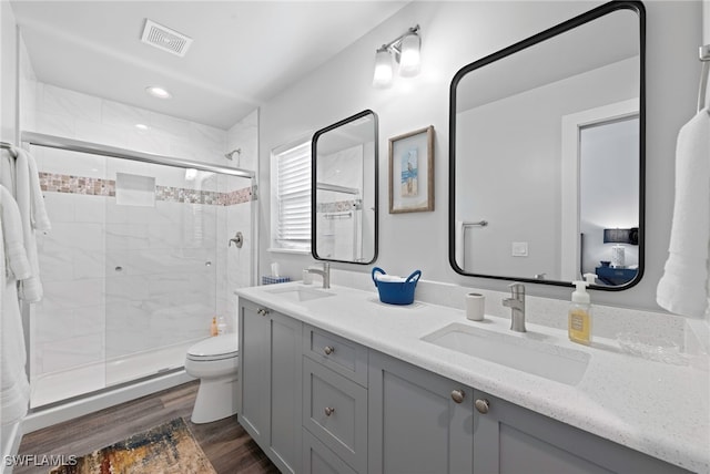 bathroom featuring hardwood / wood-style floors, vanity, toilet, and an enclosed shower