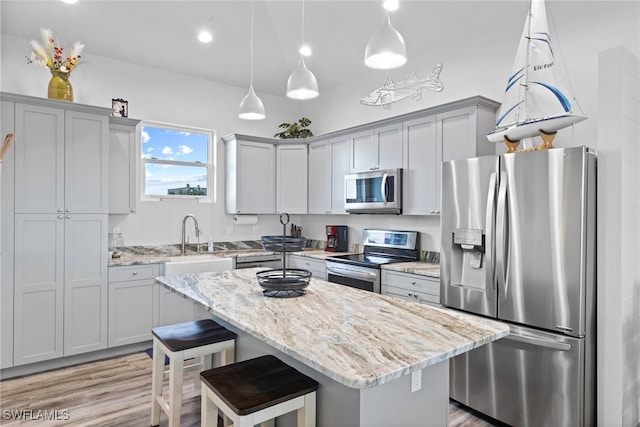 kitchen featuring light stone countertops, a center island, sink, and appliances with stainless steel finishes