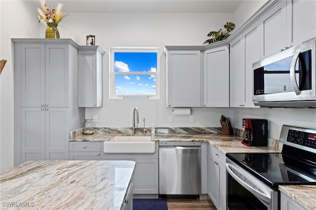 kitchen featuring gray cabinets, light stone counters, sink, and appliances with stainless steel finishes