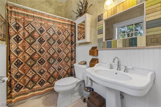 bathroom featuring sink, wooden walls, a shower with shower curtain, toilet, and radiator heating unit